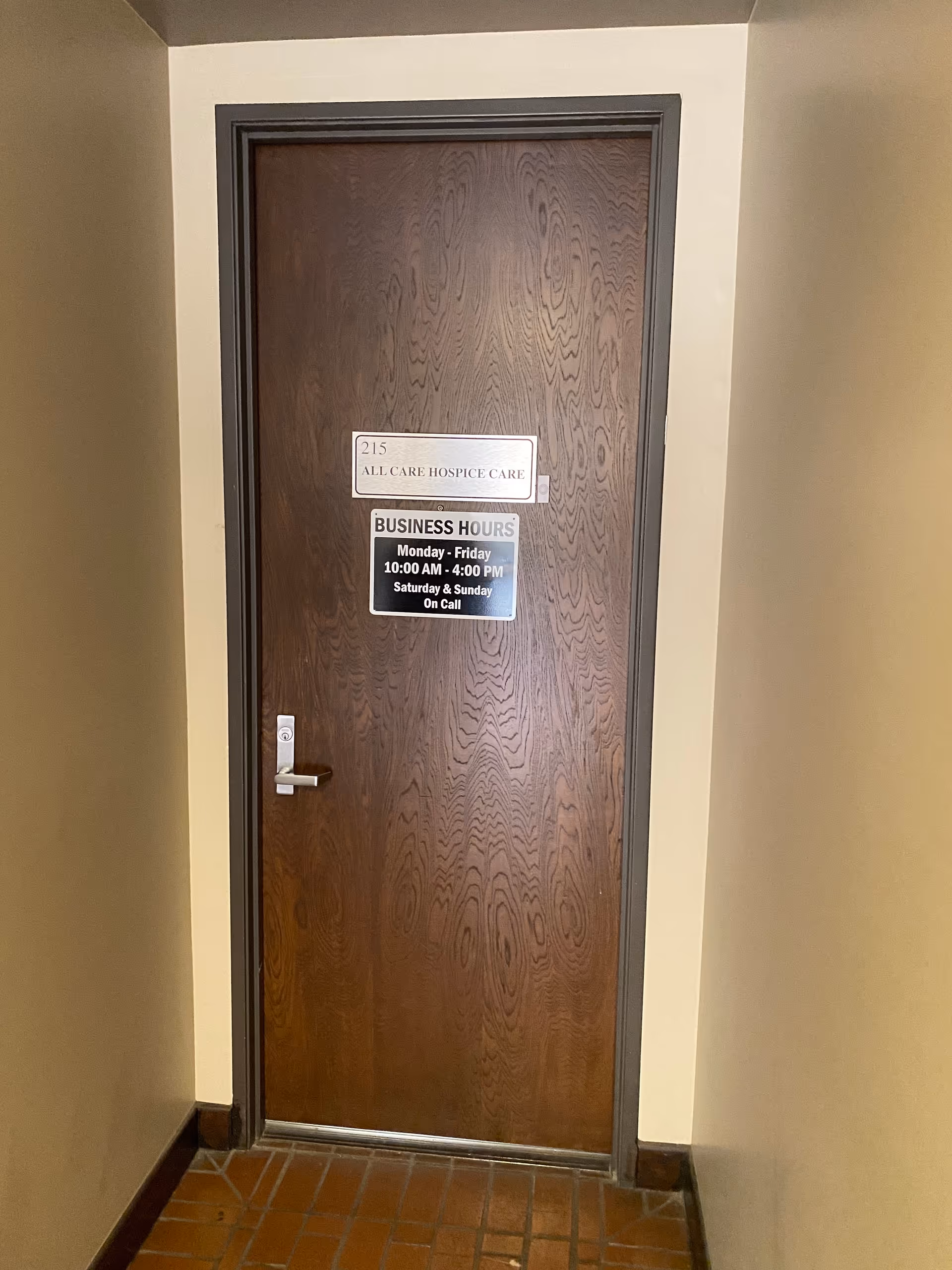 Wooden interior door with All Care Hospice Care signage and business hours posted.