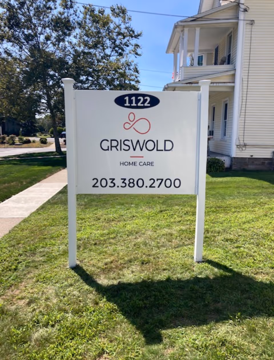 Griswold Home Care sign on a grassy lawn in front of a white building.
