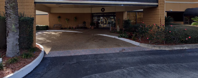 Entrance canopy over a driveway with landscaped shrubs and seating at Premier Assisted Living.