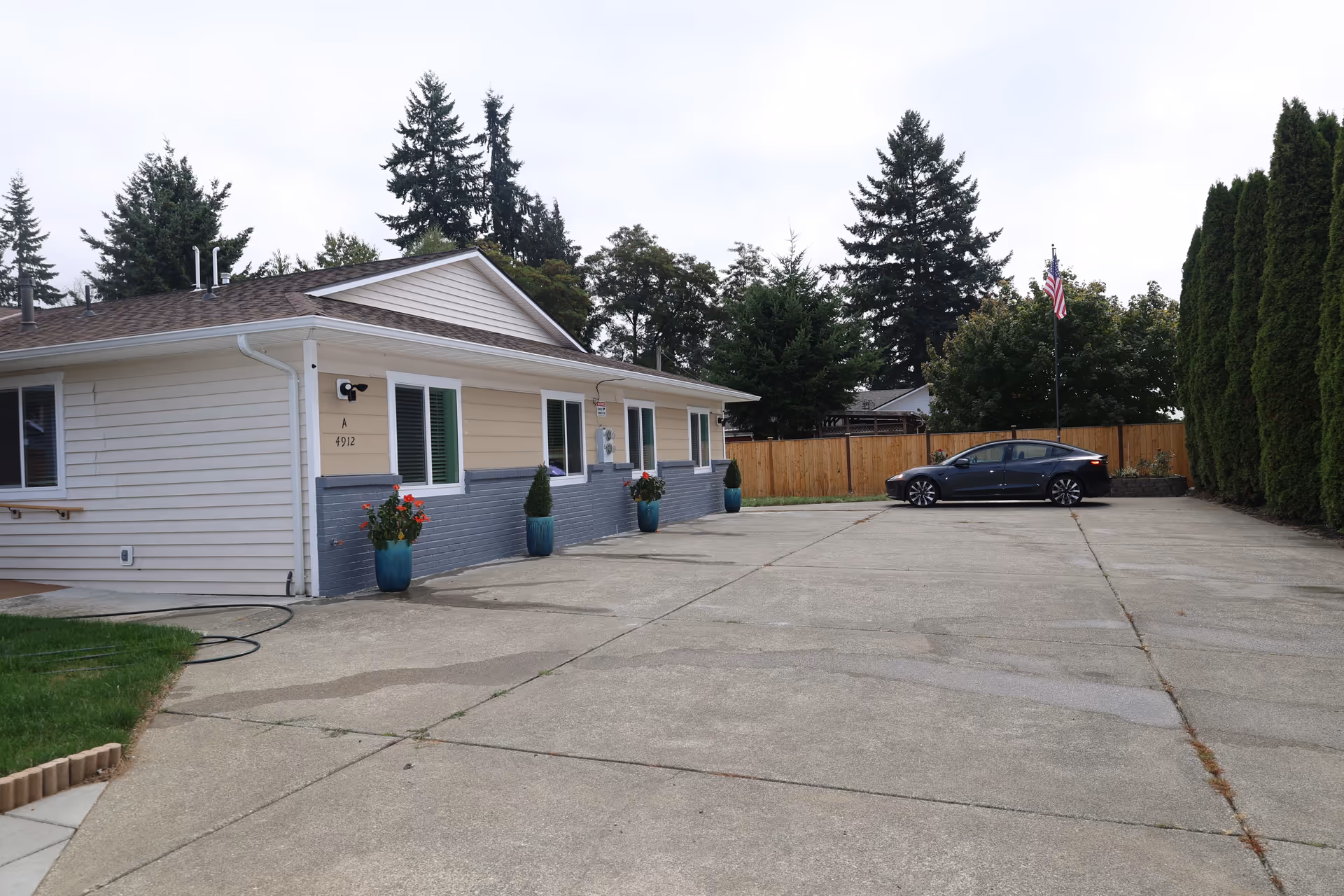 Exterior view of a single-story Abode Care AFH building with potted plants and a car.