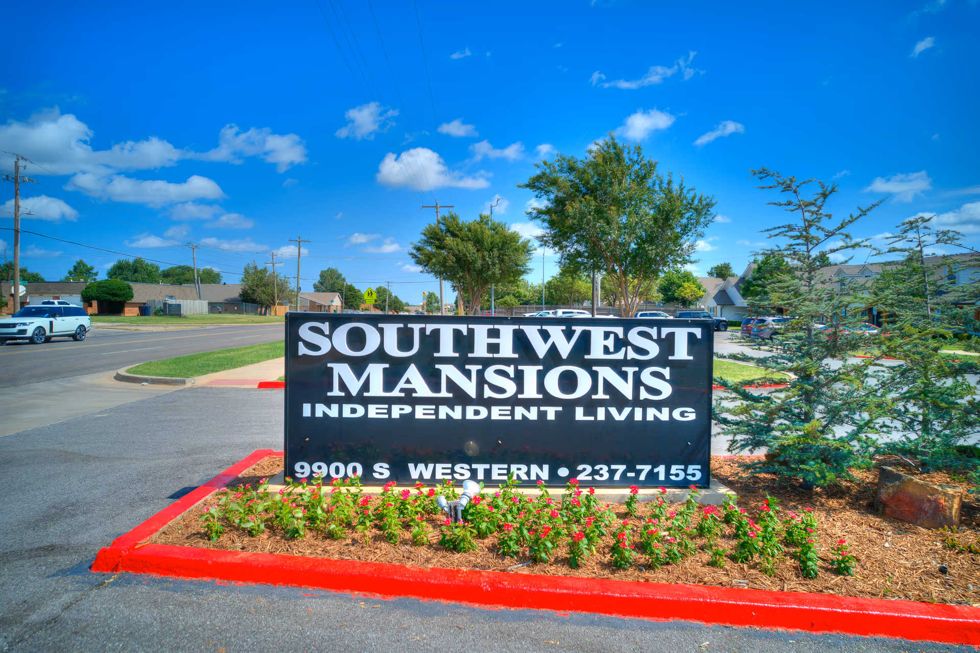 Large black sign reading Southwest Mansions Independent Living in a landscaped parking lot