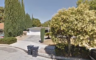 Exterior view of a senior living facility with driveway and trees