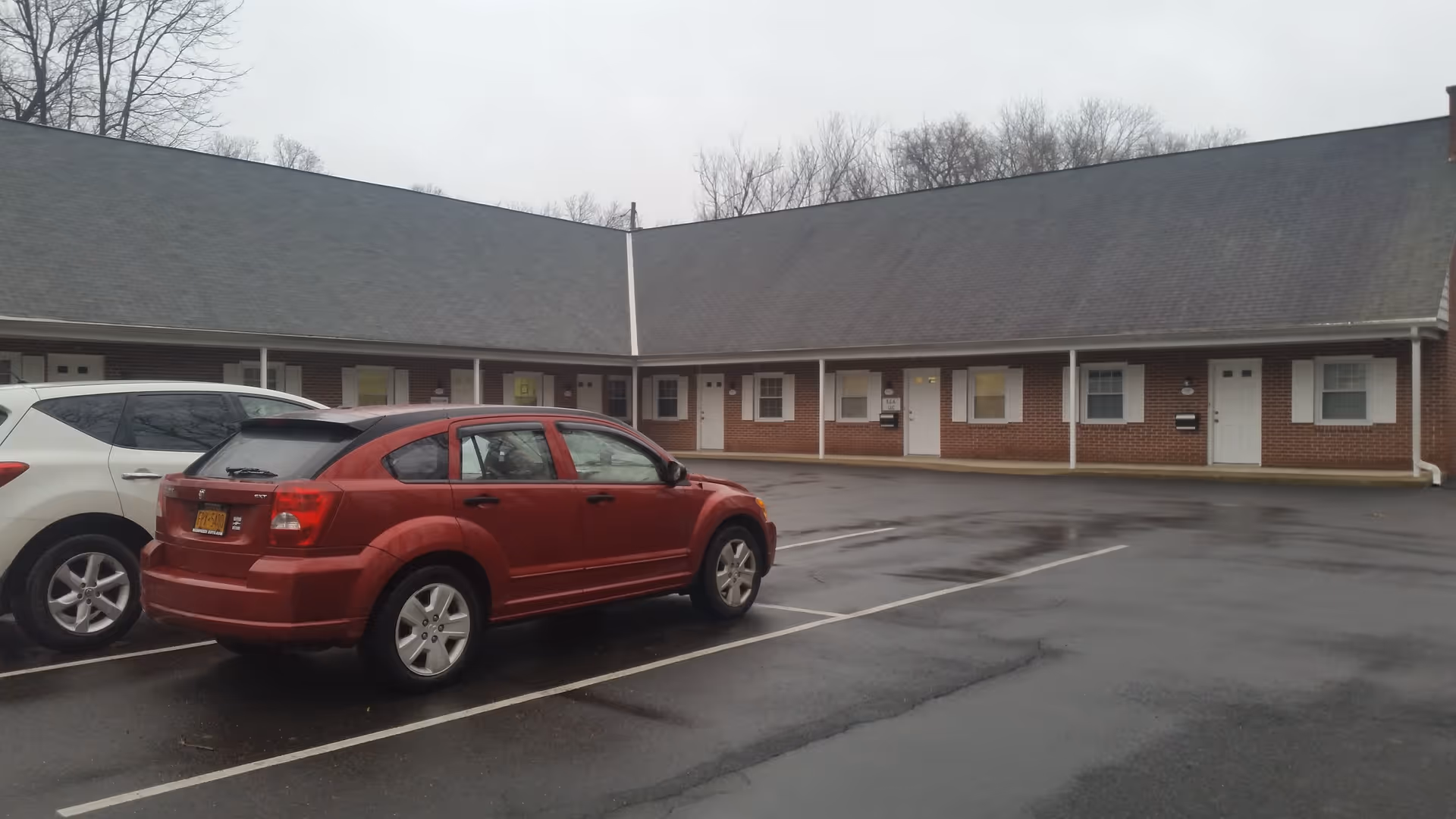 Red SUV parked in front of a single-story brick senior living facility.