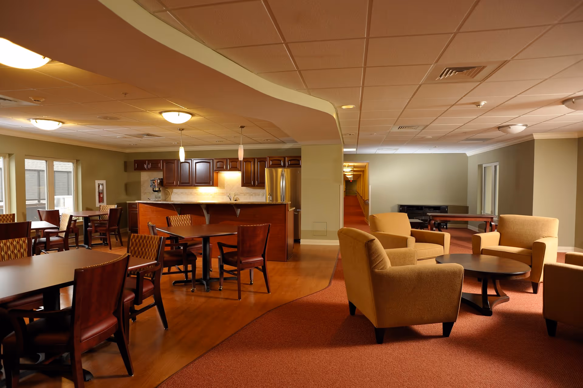 Spacious senior living common area with couches, tables, and a kitchen island.