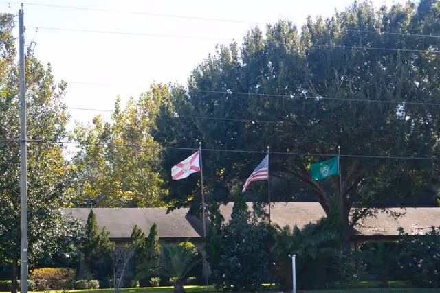Exterior view of New Horizon Share Home senior living facility with flags and trees.