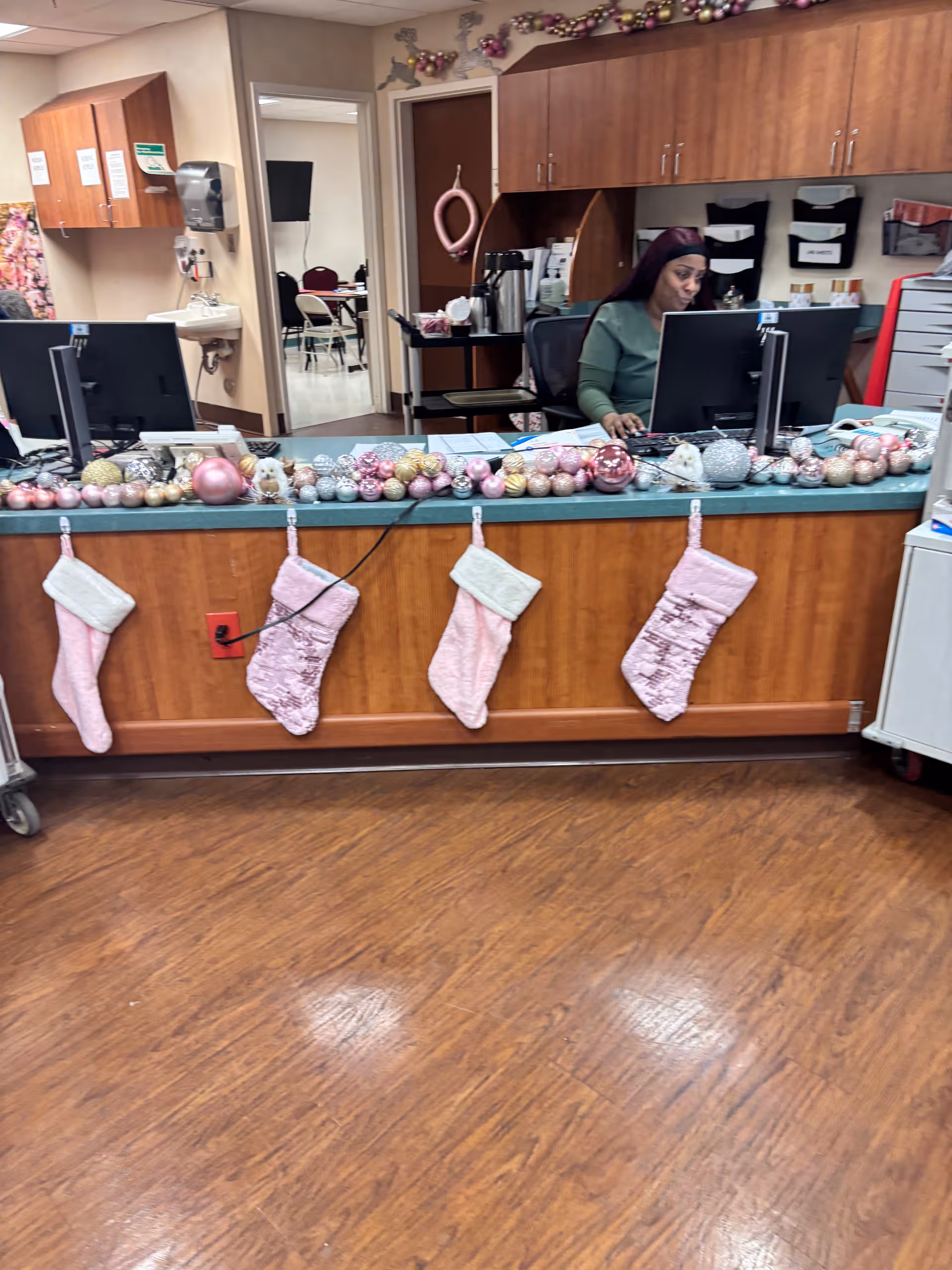 Reception desk with Christmas stockings and ornaments, a staff member at a computer.
