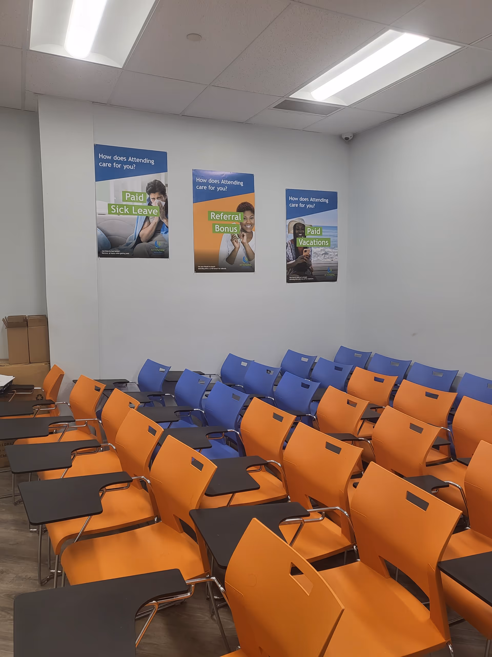 Rows of orange and blue chairs with attached desks in a training room.