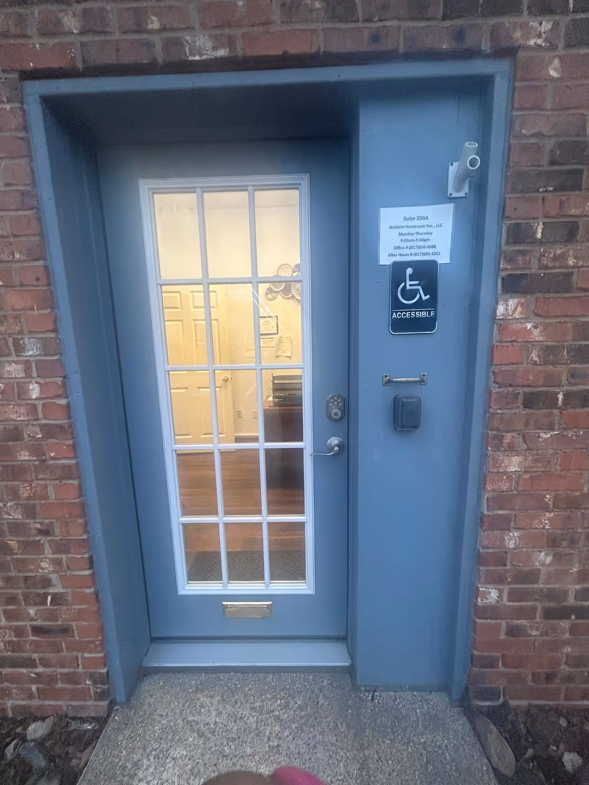 Blue door with glass panes in brick exterior near an accessibility sign.