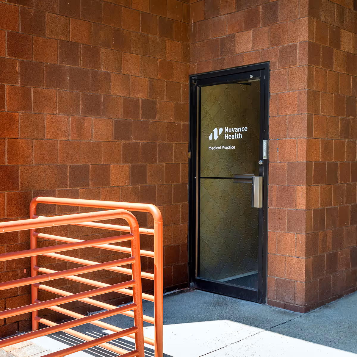 Brick exterior wall with a glass door labeled Nuvance Health Medical Practice and an orange railing.