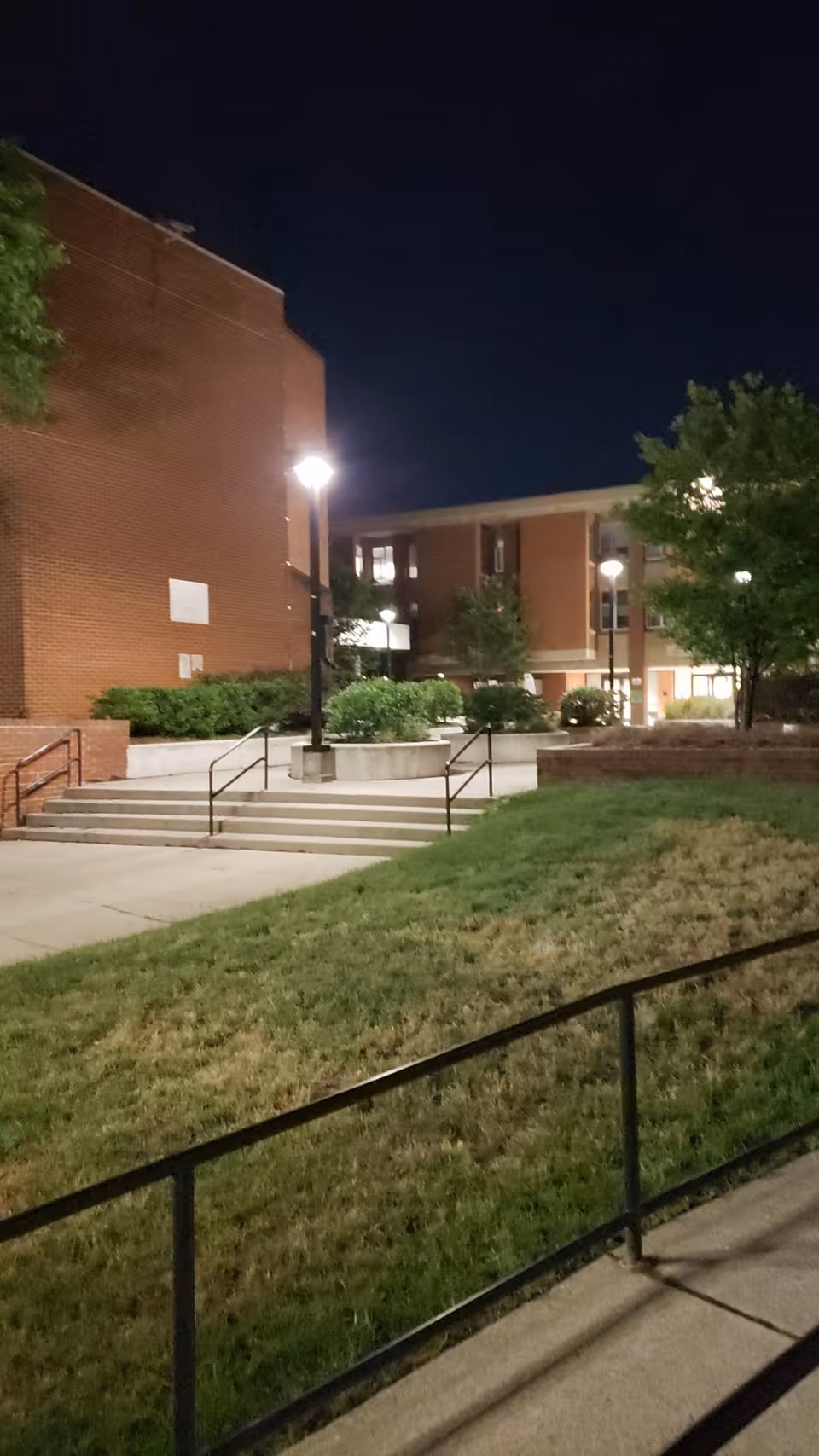 Night view of Abrams Hall Senior Apartments exterior with brick building and lit pathways