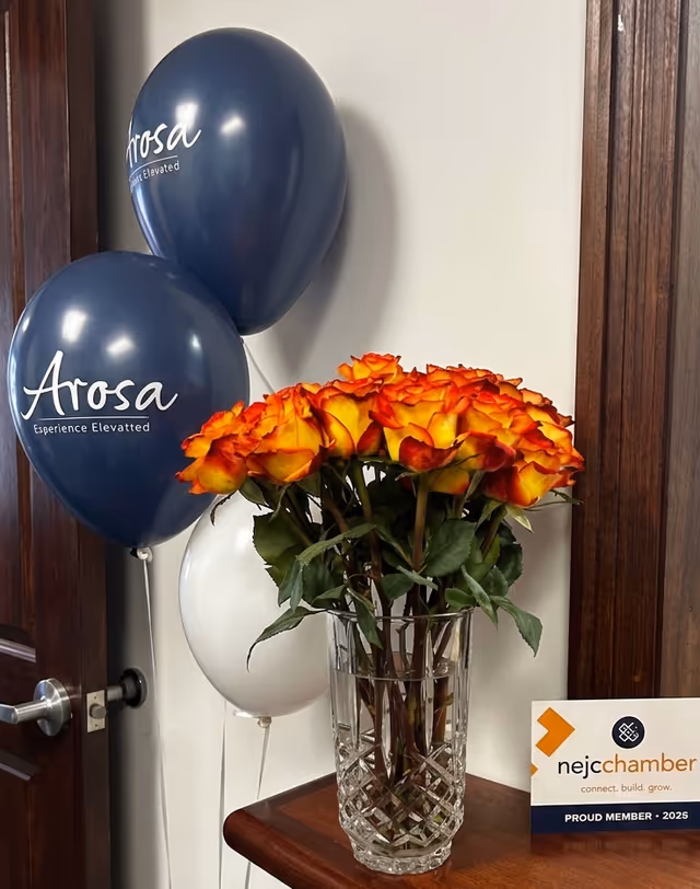 Close-up of Arosa Kansas City navy balloons and orange roses by a doorway.