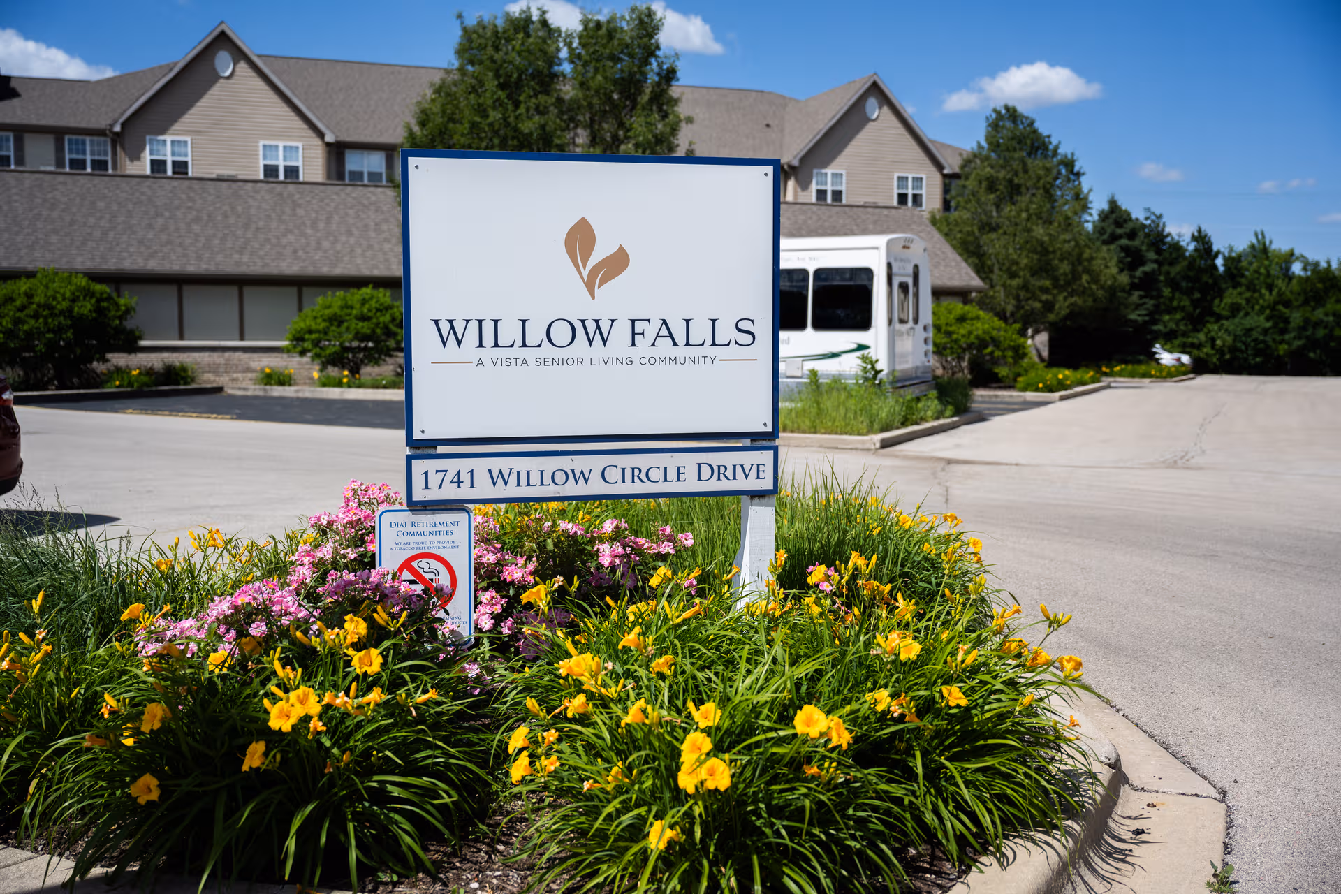 Willow Falls Senior Living sign with flower bed and building behind.