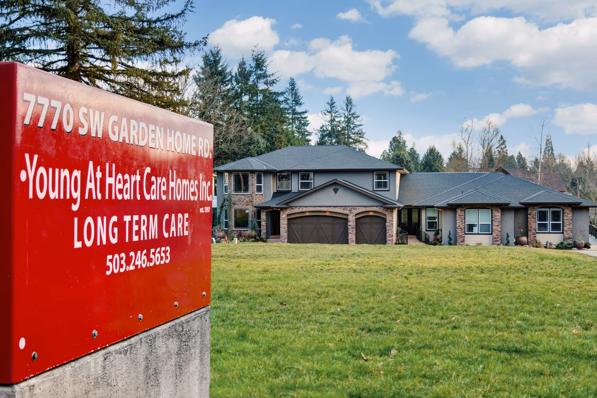 Red sign for Young at Heart Care Home fronts a two-story brick-and-stone senior facility.