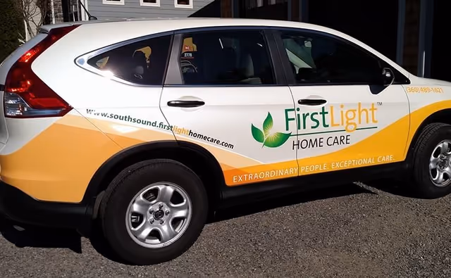 Branded FirstLight Home Care vehicle parked outdoors with logo and contact information.