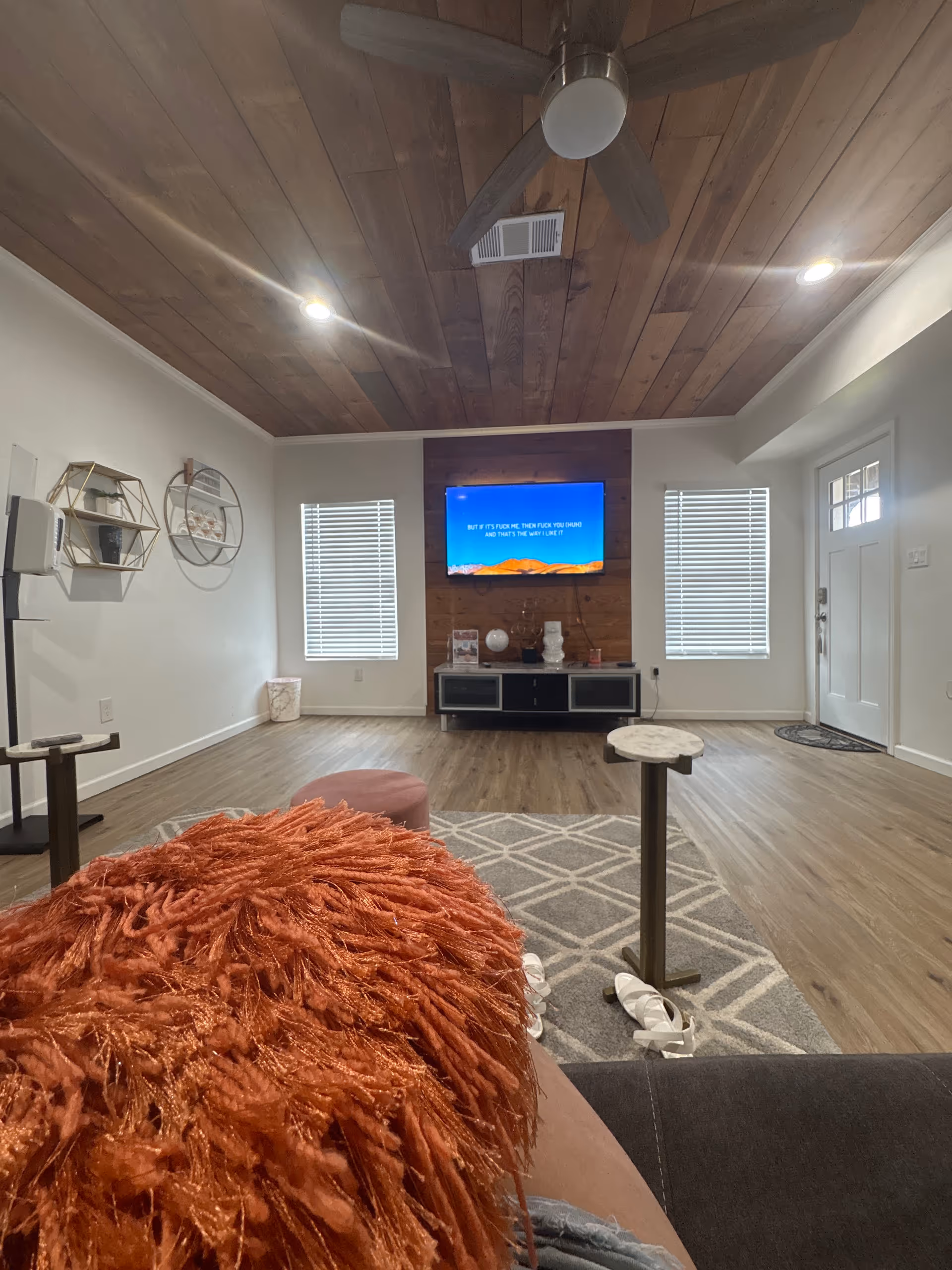 Cozy living room with wood-paneled ceiling, TV on accent wall, and seating.