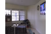 A resident room with a bed, dresser, window, and wall-mounted TV in a care facility.