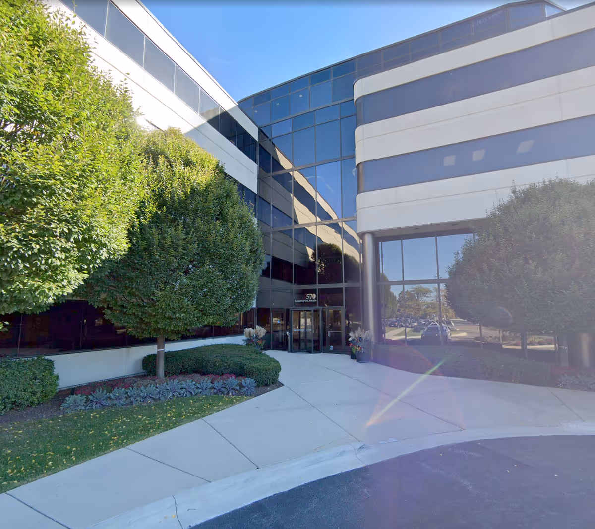 Modern glass-front facility exterior with landscaping and a welcoming entrance.