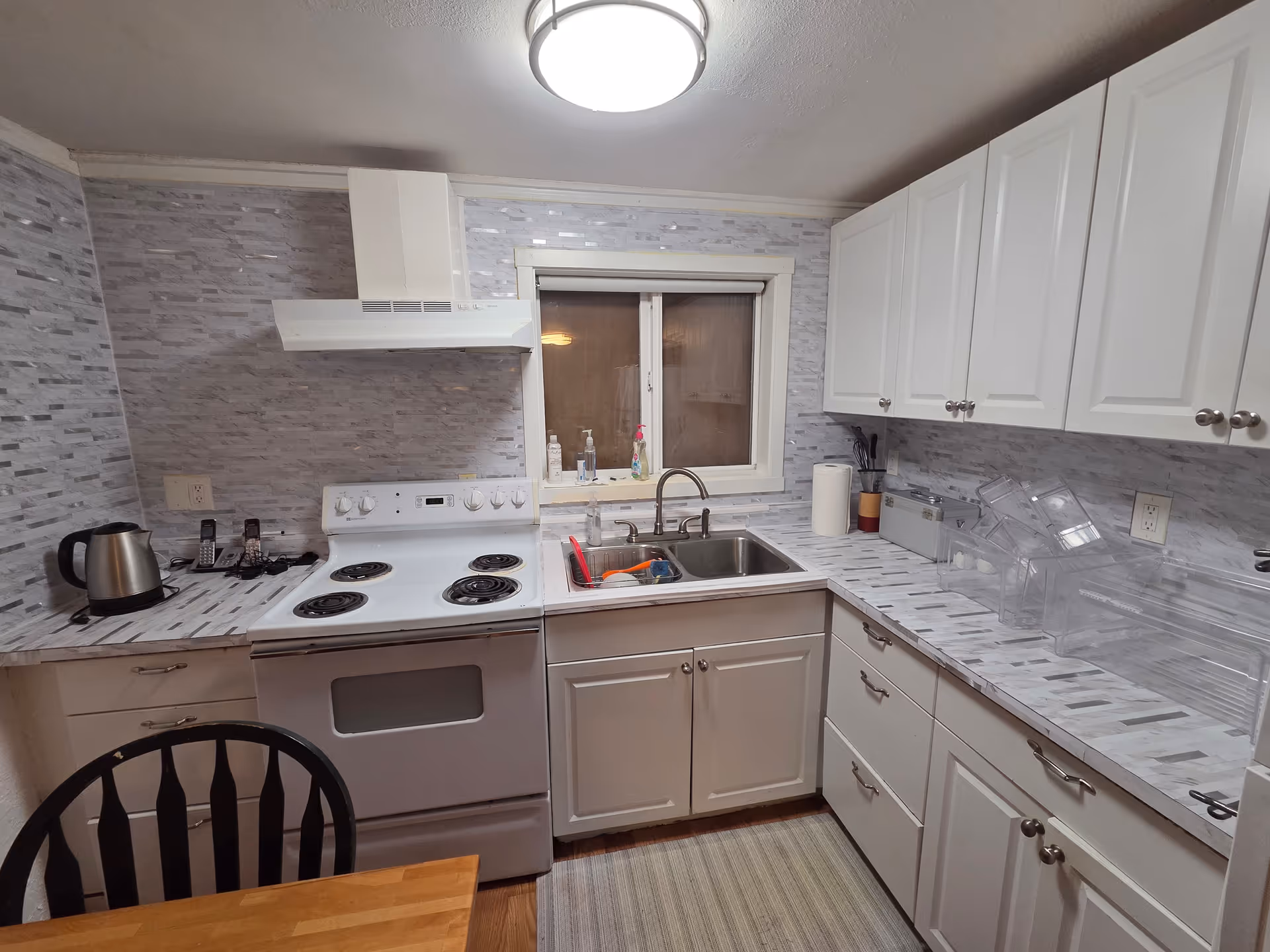 White kitchen with stove, sink, and cabinets in a compact, tiled space.