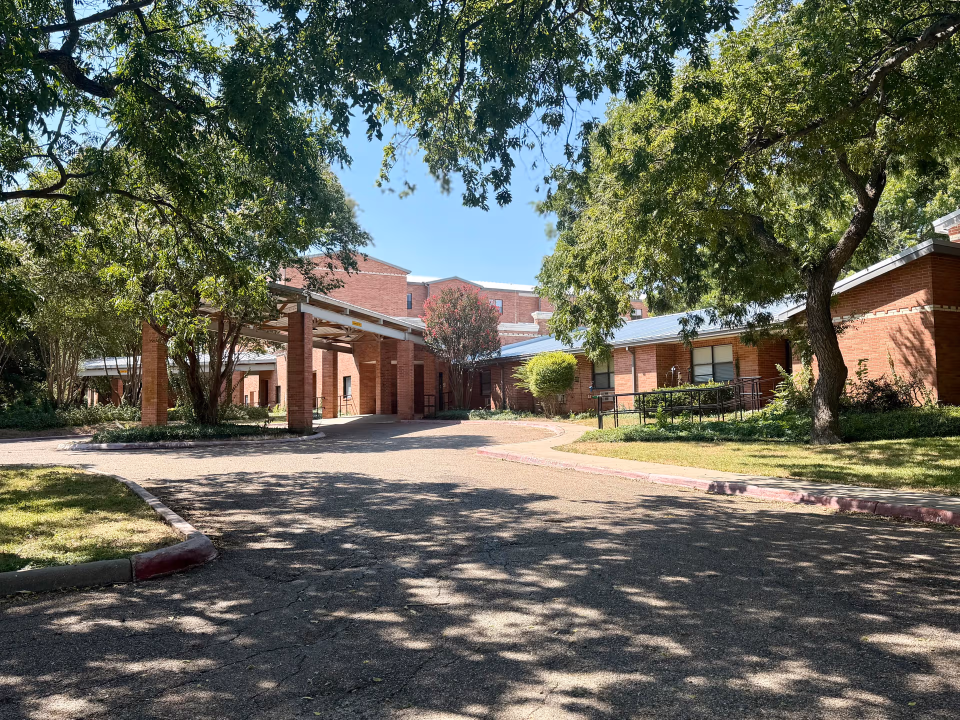 Brick building exterior with a covered entrance at Ridgecrest senior living campus, surrounded by trees.