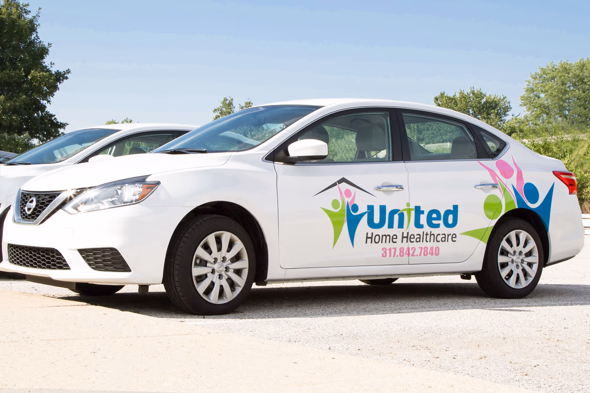 White sedan with United Home Healthcare logo parked outdoors.