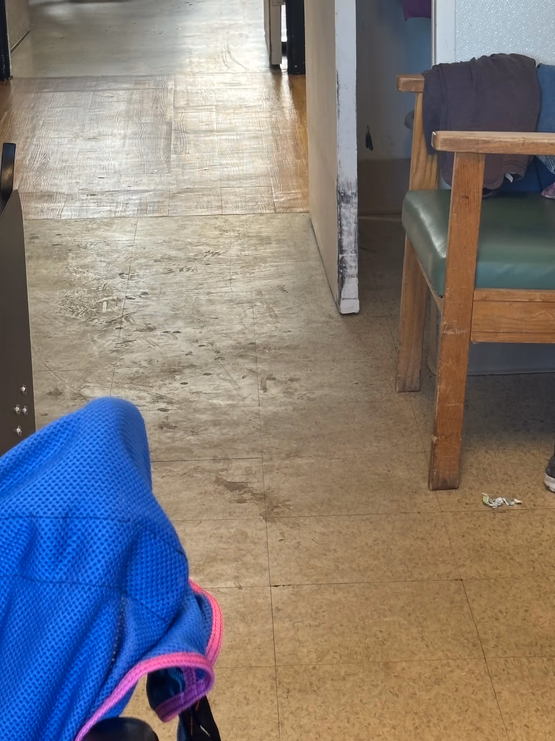 Narrow hallway in Mountain View Care Center with worn floors and a chair on the right.