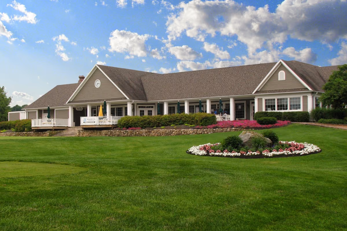 Single story senior living facility with a large manicured lawn and circular flower bed in front.