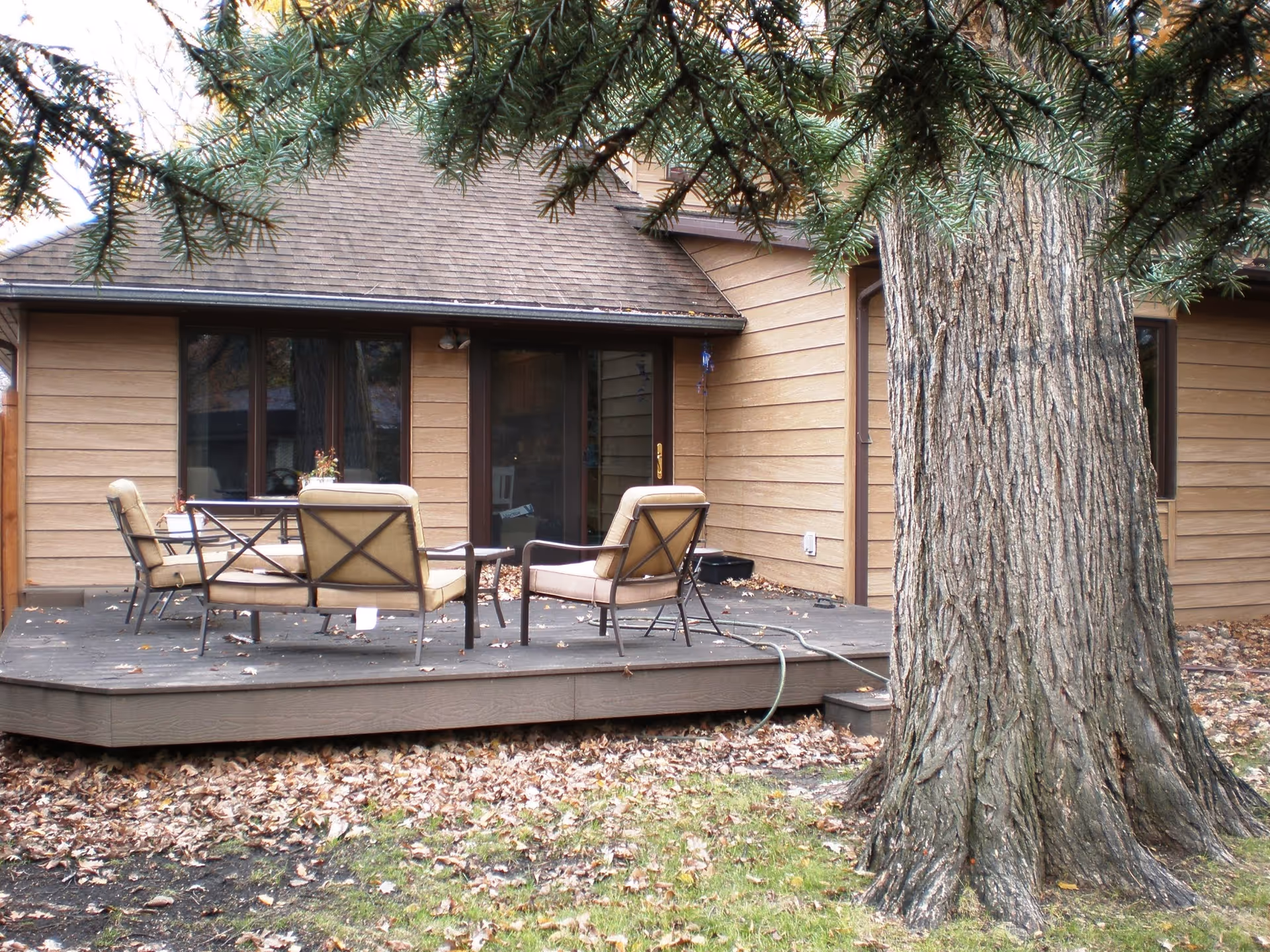 Exterior view of Tranquility Place with a wooden deck, seating, and a large tree.