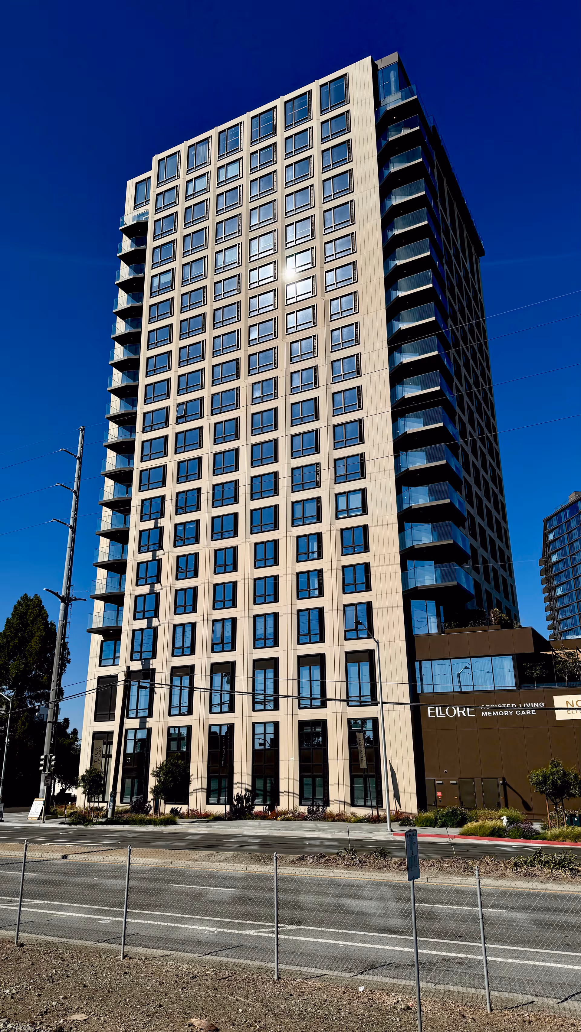 Tall Ellore senior living building with many windows against a blue sky.