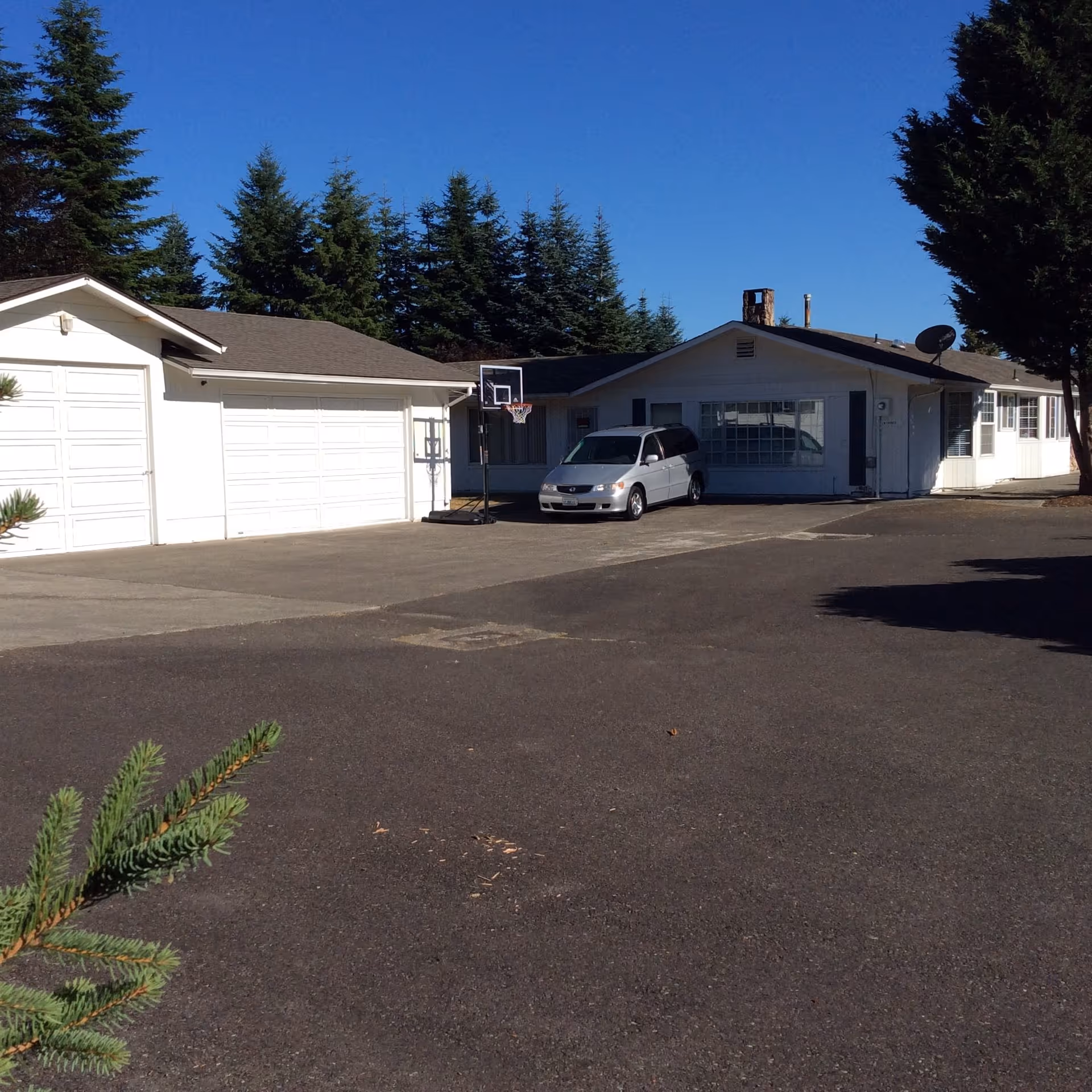 White single-story facility with attached garages and a van parked in the driveway.