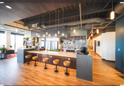 Open, modern senior living kitchen with island, bar stools, and geometric accent wall.