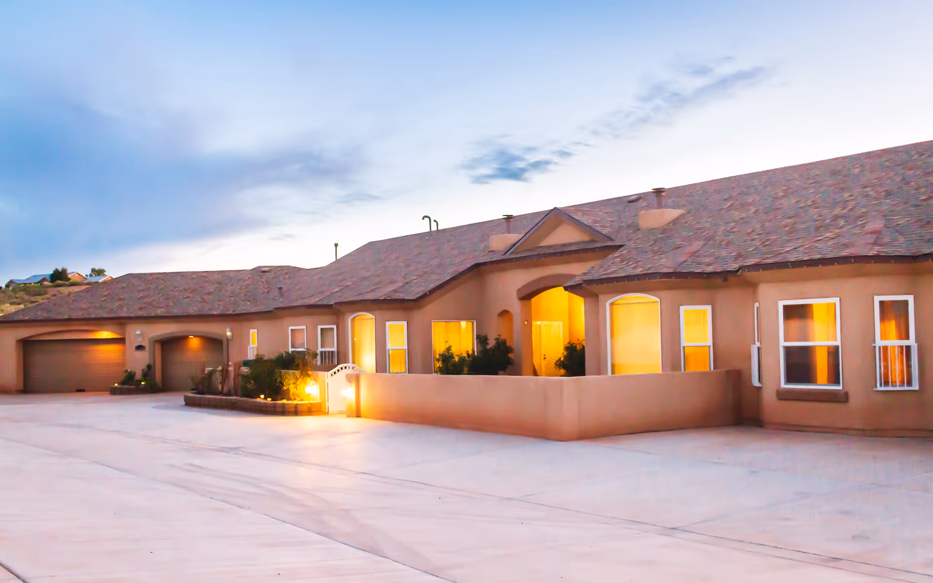 Single-story senior living facility exterior with an illuminated entrance at dusk.