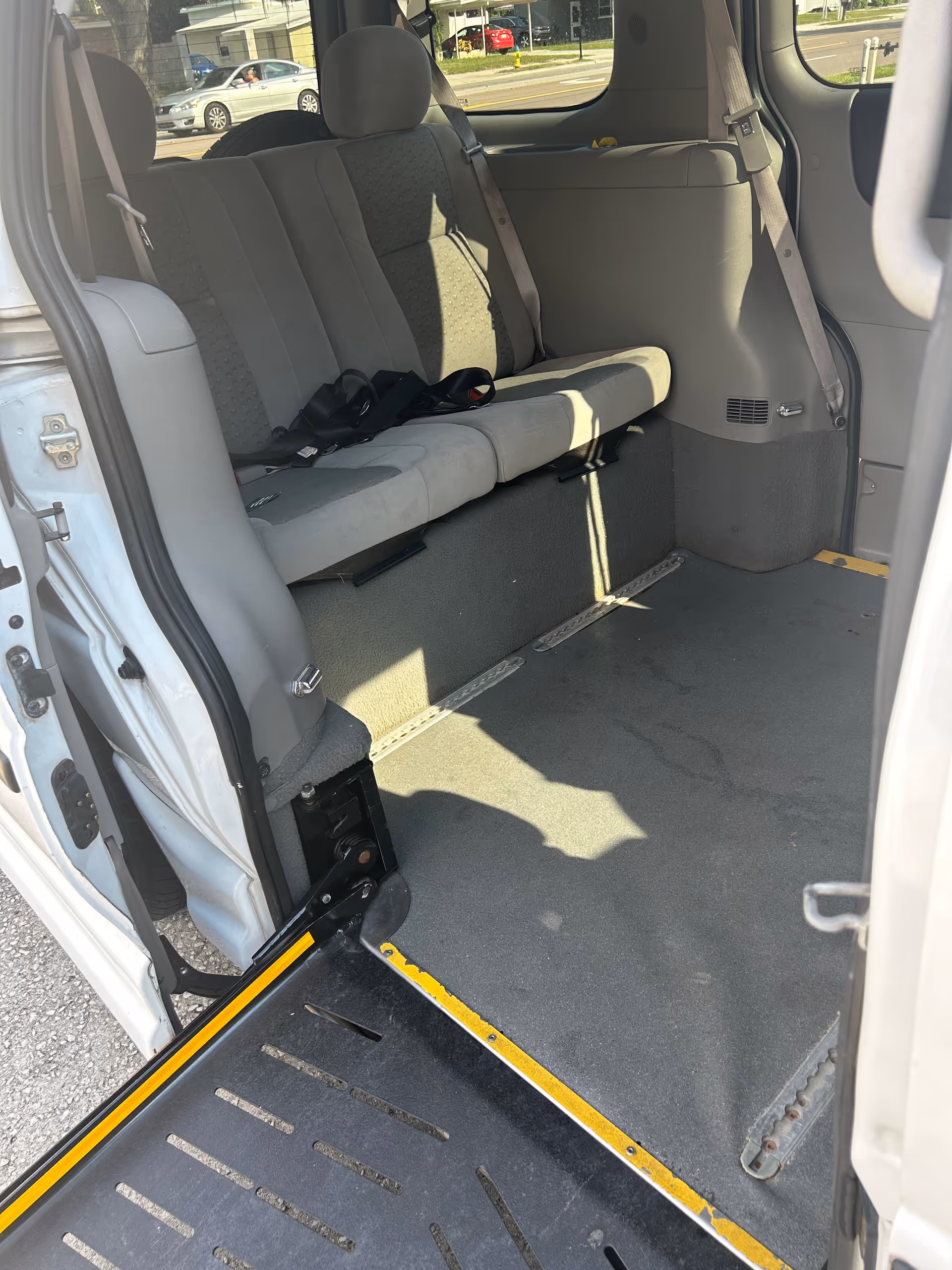 Interior of a passenger van with bench seats and a lowered wheelchair ramp.