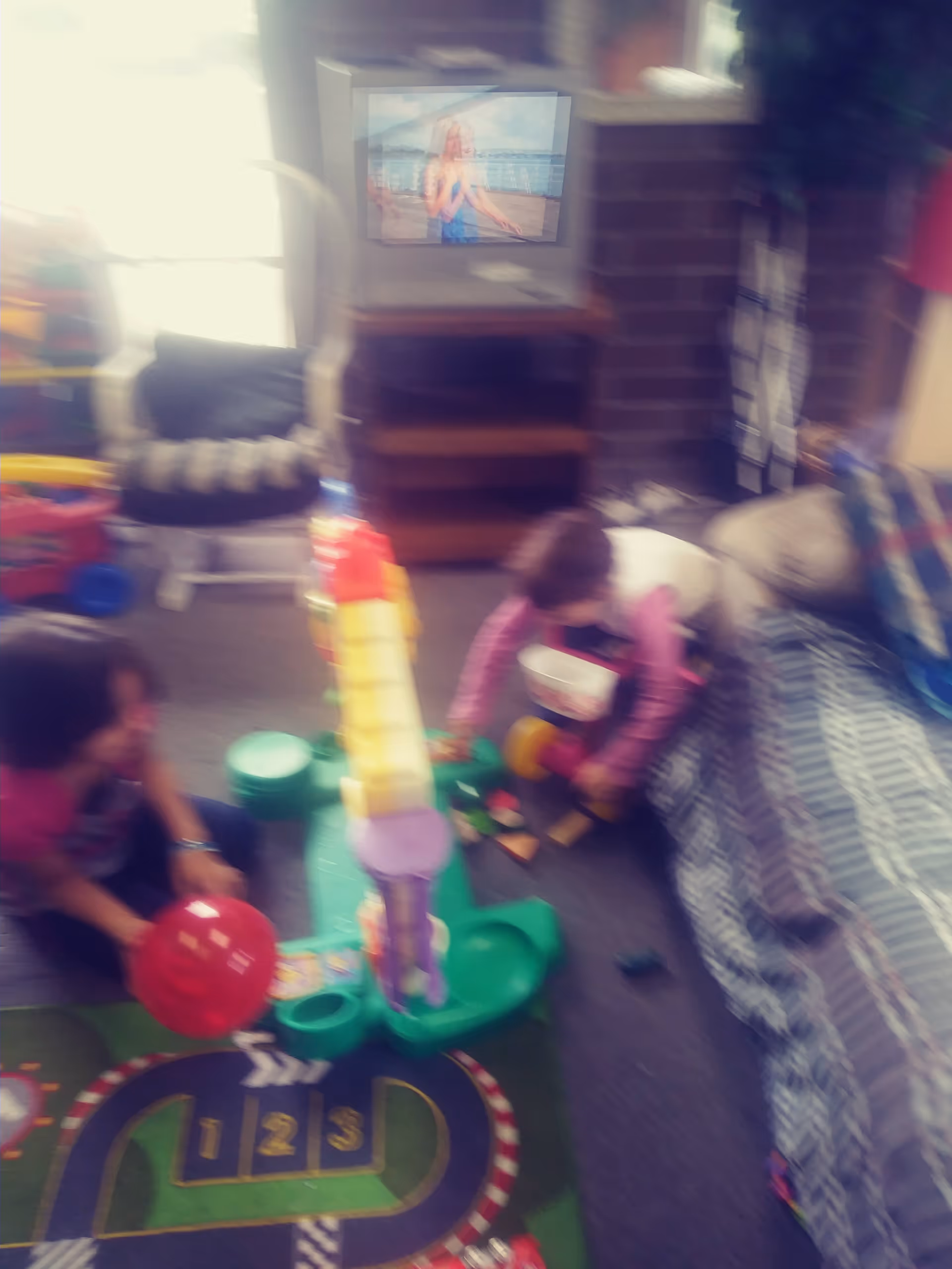 A cozy living room with toys on the floor and a TV on a stand.