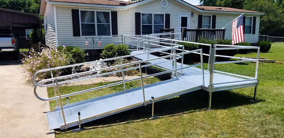 Metal accessibility ramp leads to a single-story facility entrance with an American flag.