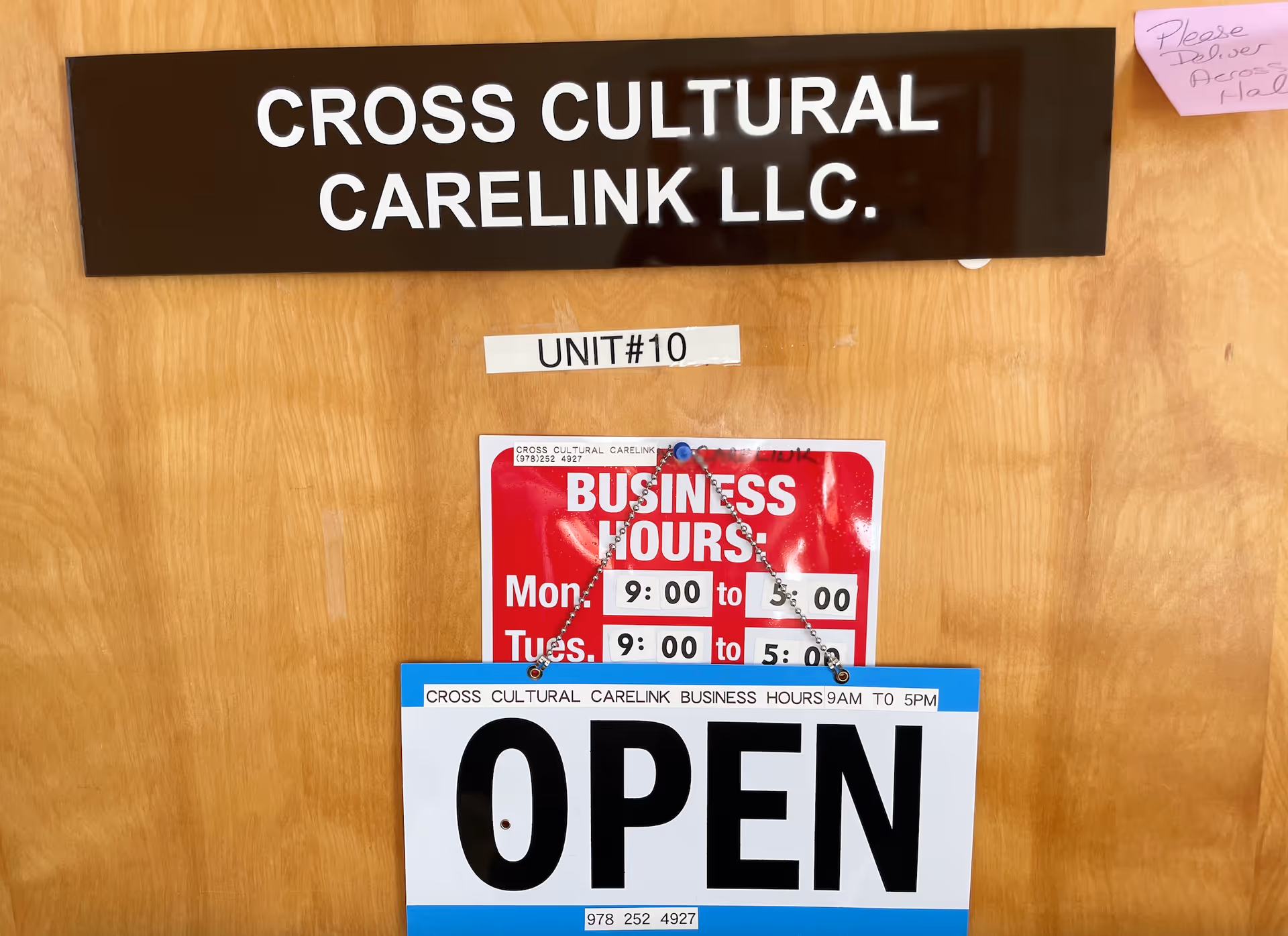 Wood door displaying Cross Cultural CareLink LLC, Unit #10 tape, and OPEN sign.