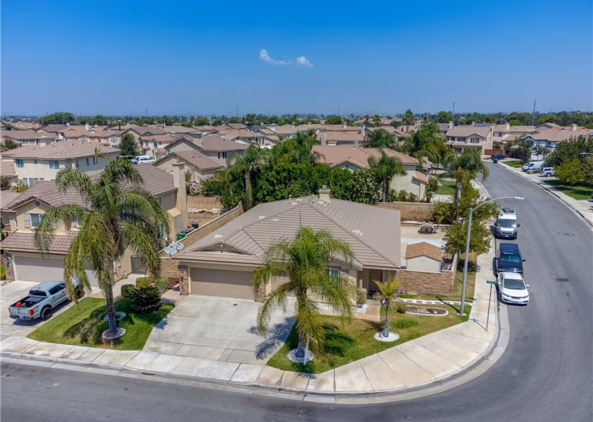 Aerial view of a suburban cul-de-sac with beige houses and palm trees.