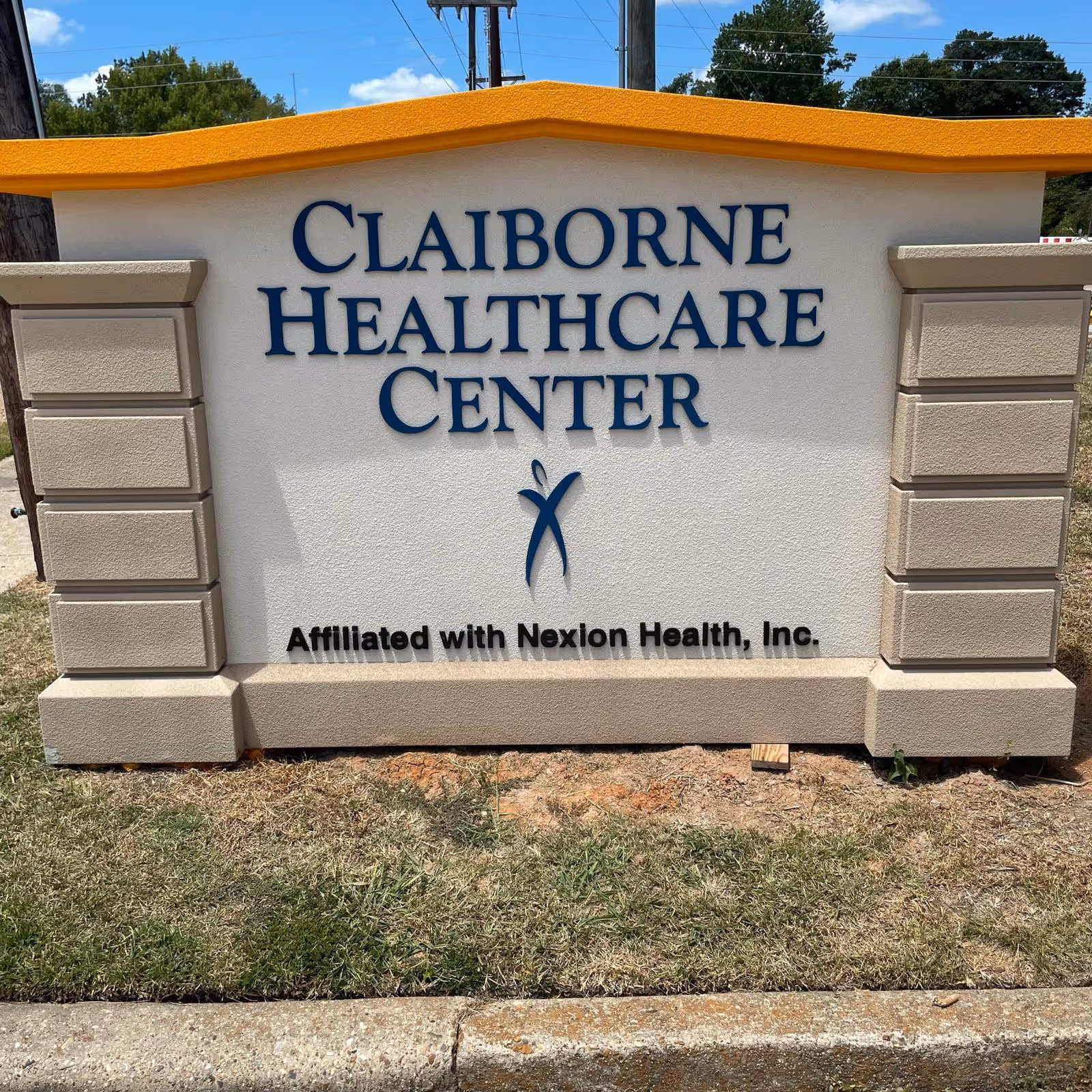 Outdoor monument sign reading "Claiborne Healthcare Center" with smaller text "Affiliated with Nexion Health, Inc." on a grassy curb.