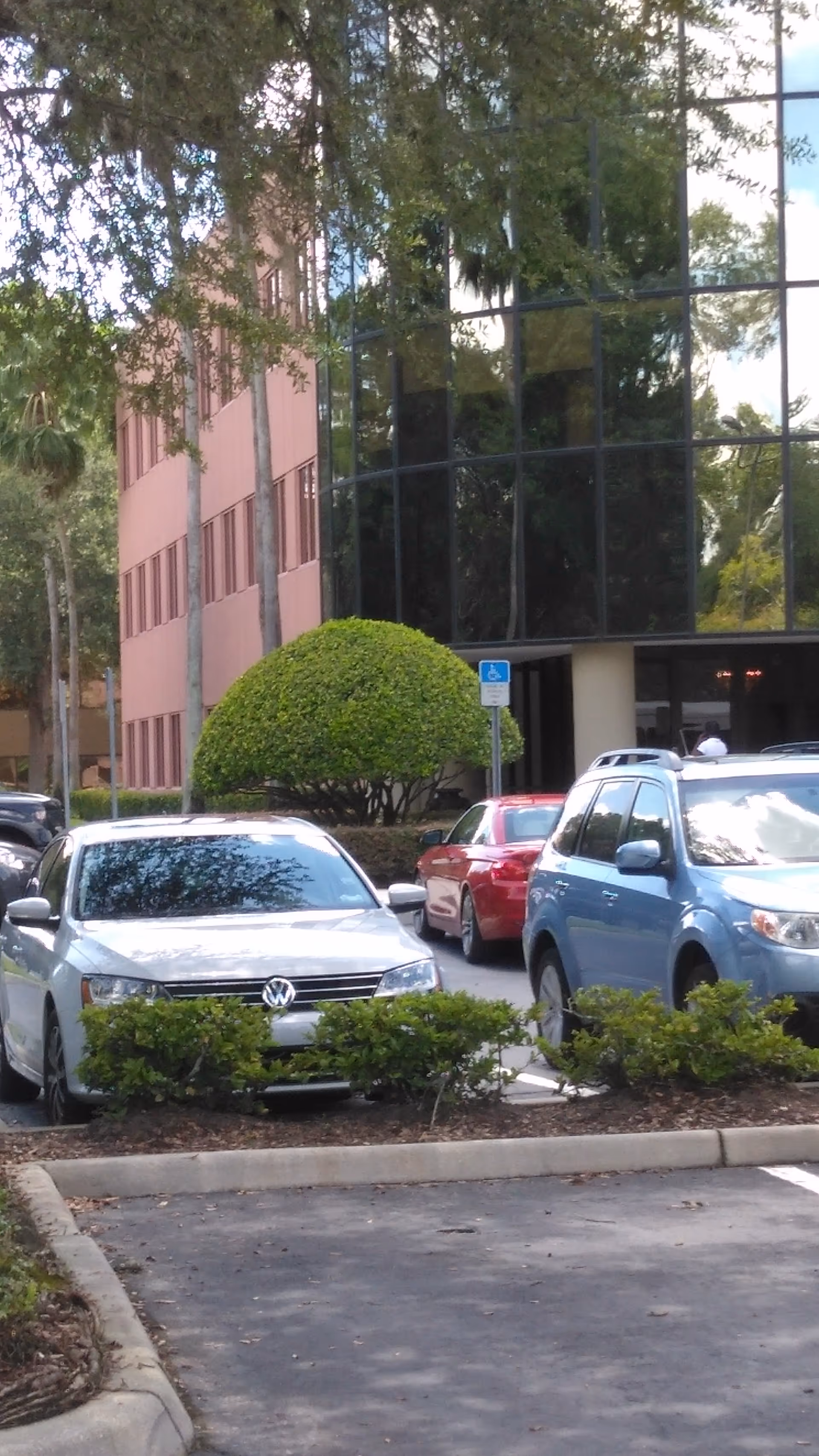 Exterior view of a modern building with glass windows and parked cars in front.