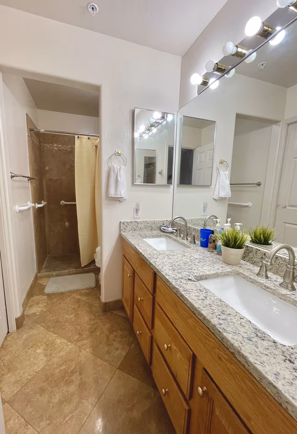 A modern bathroom with double sinks, a shower, and mirrors.