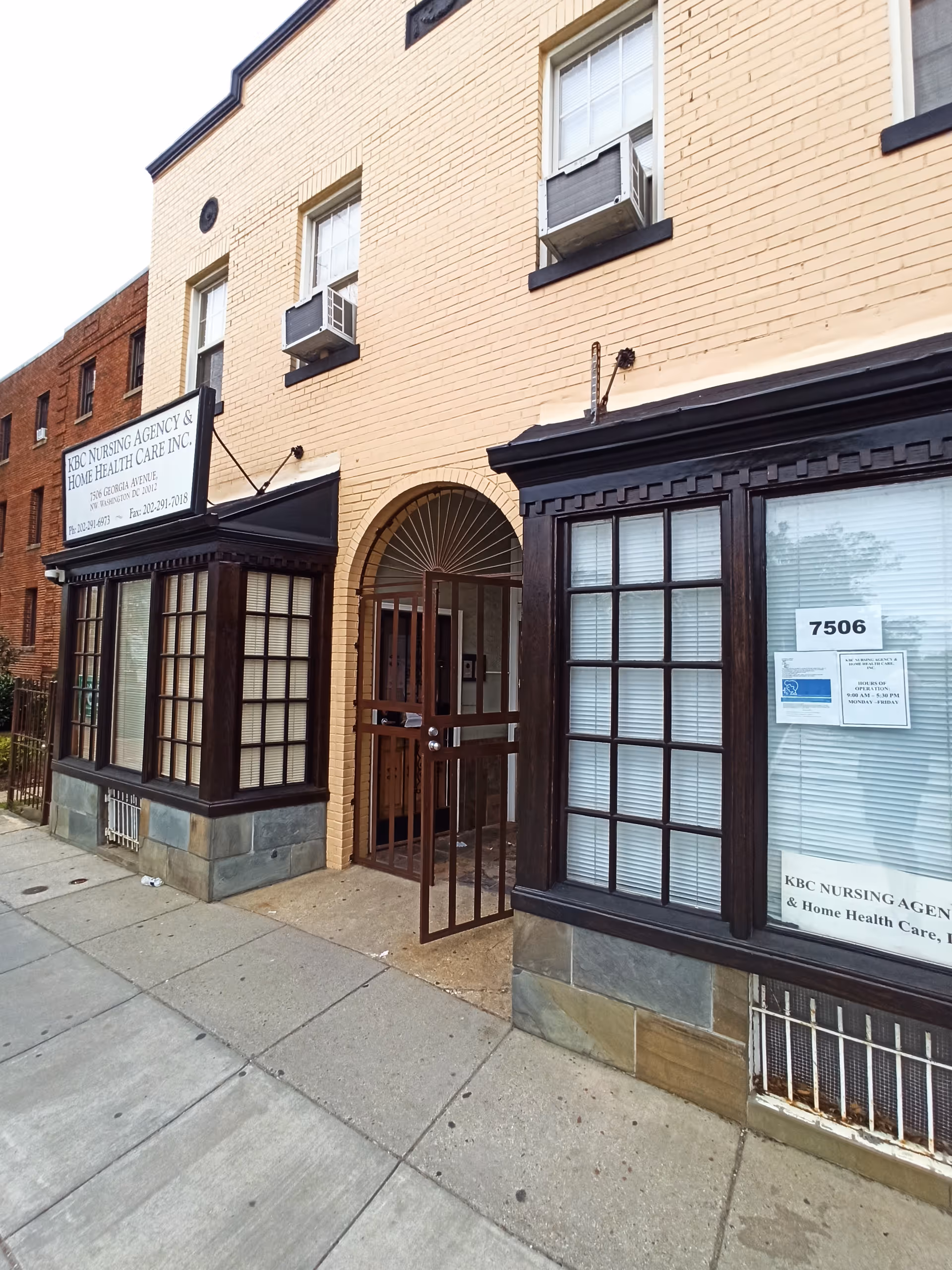 Brick building exterior with a gated arched doorway and nursing agency sign.