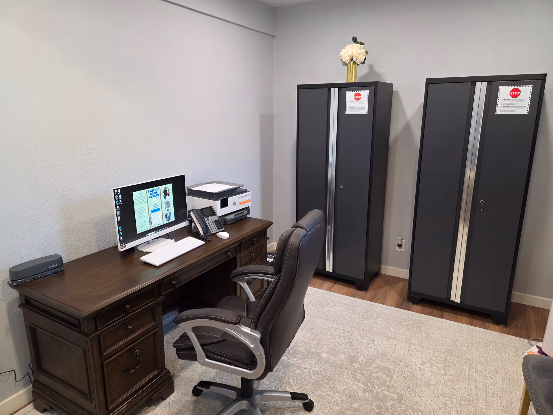 Office workspace in a senior facility with a desk, computer, printer, and two tall storage cabinets.