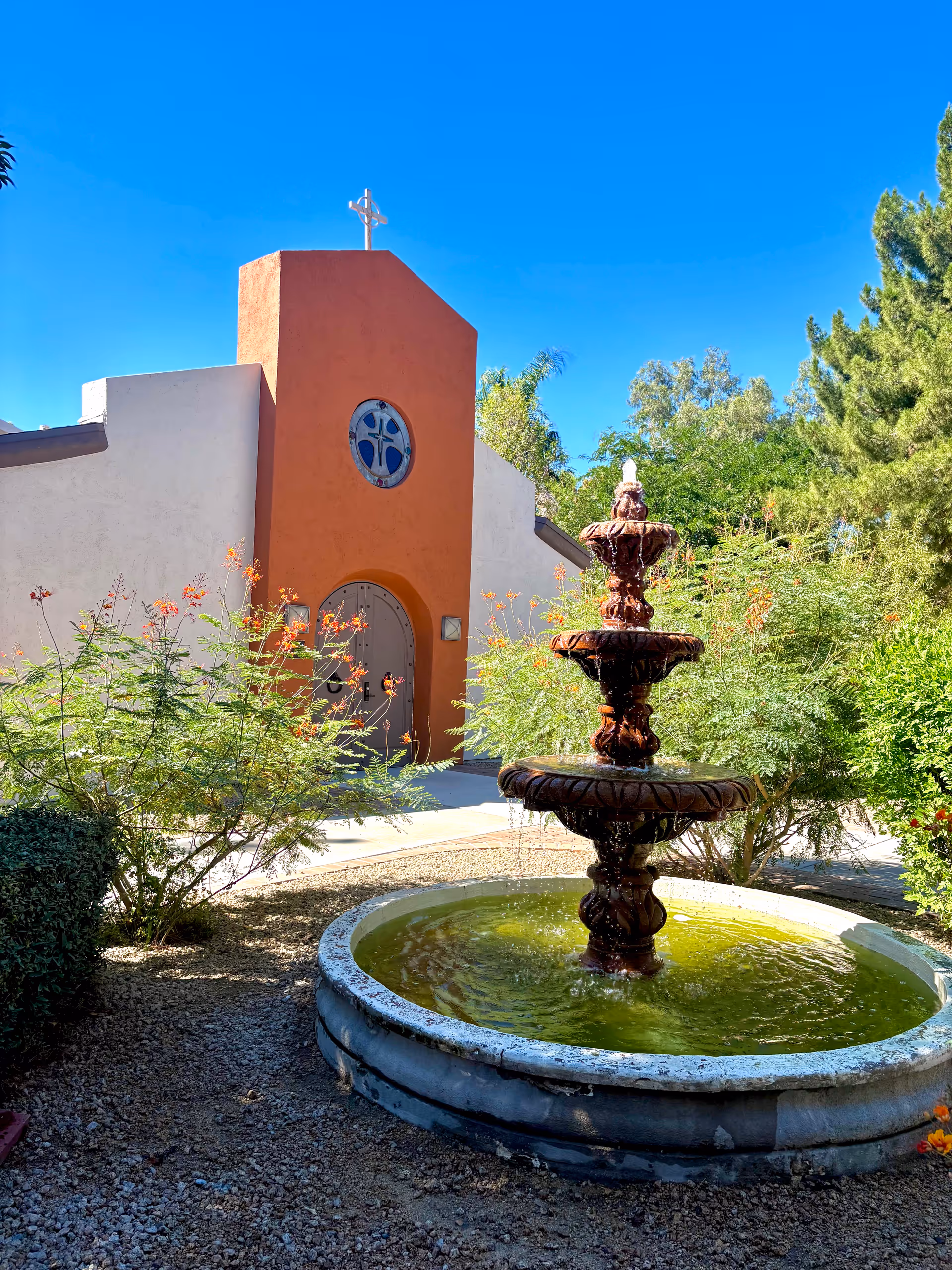 A small courtyard fountain in front of a peach-colored building.