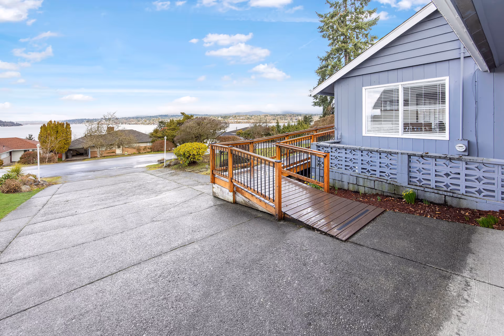 Blue facility exterior with wooden ramp, railing, and scenic hillside view.