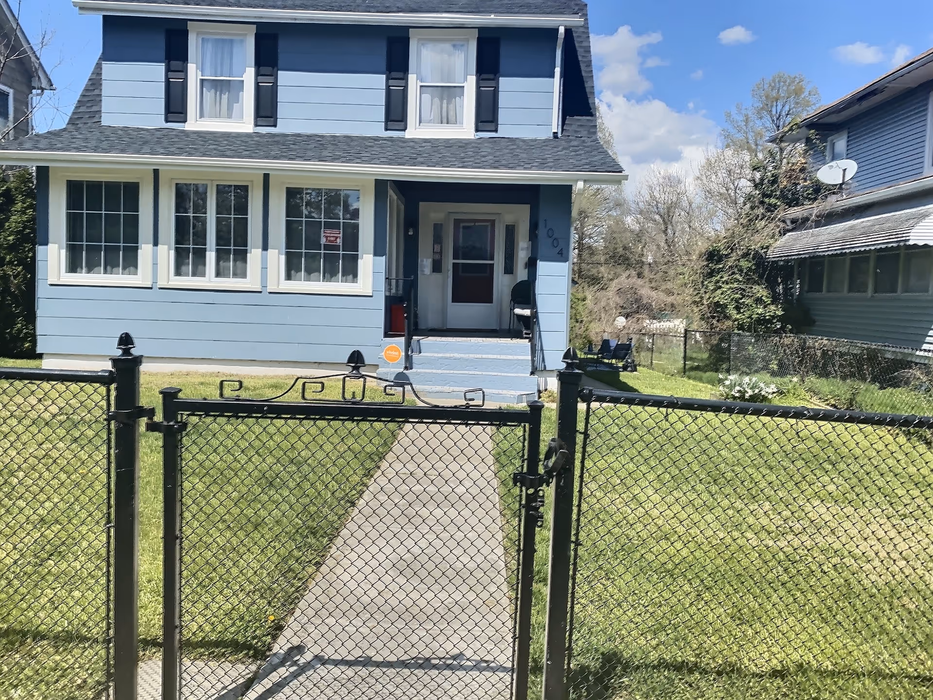 Blue two-story assisted living residence with front gate, walkway, and trimmed lawn.