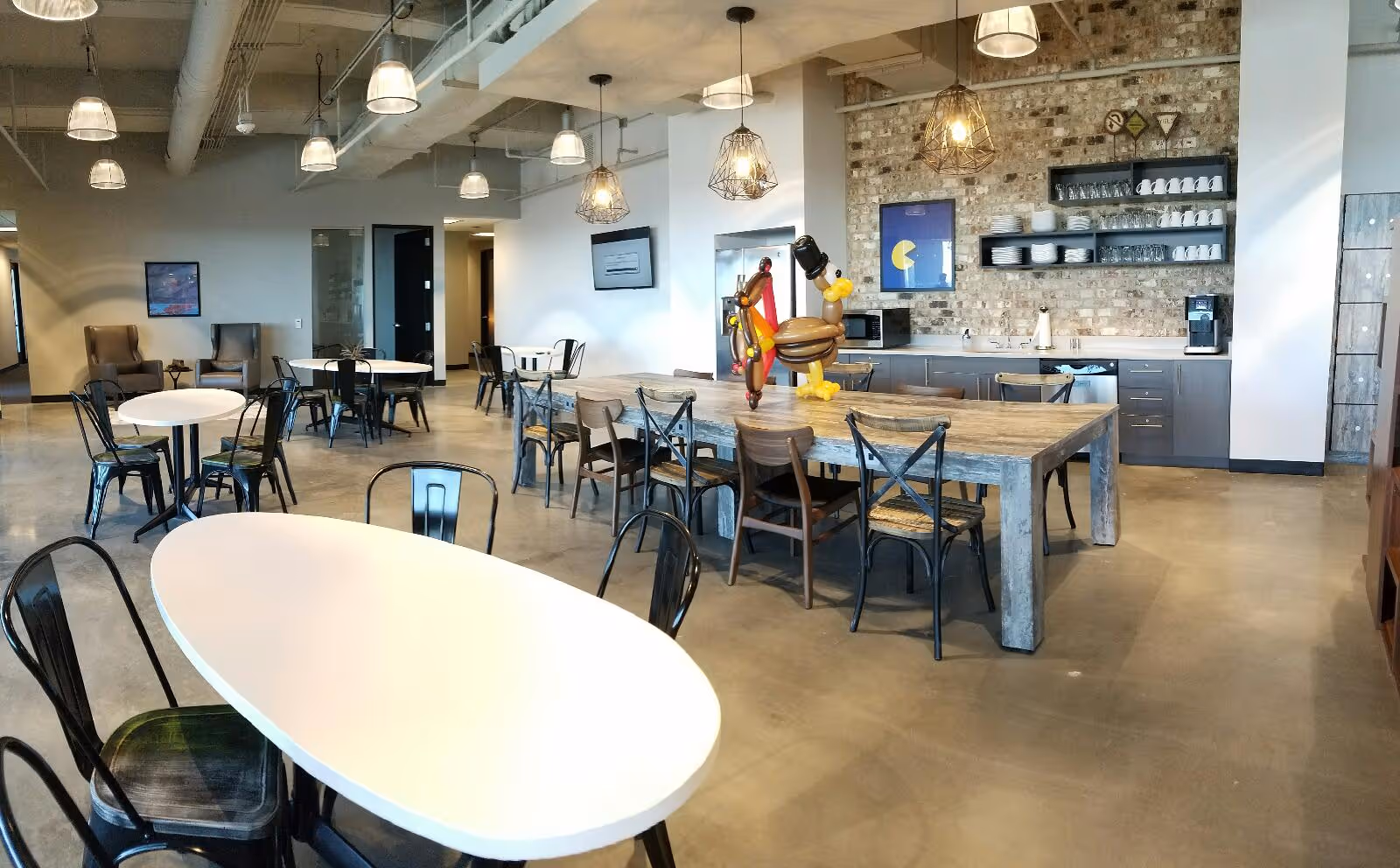Spacious, modern senior living dining area with communal tables, chairs, and a small kitchenette.