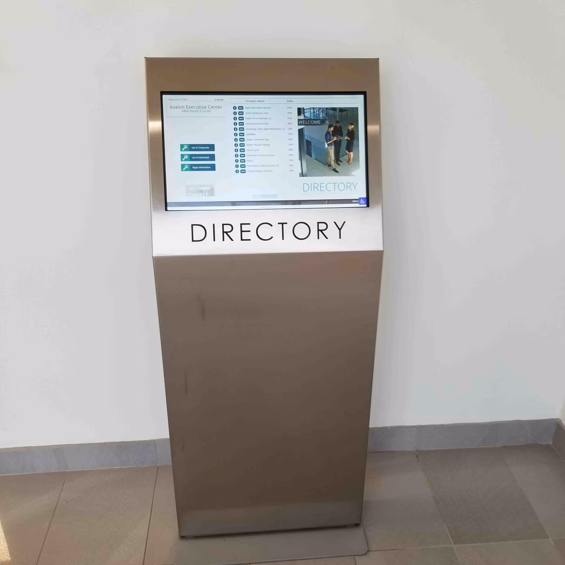 Freestanding metallic directory kiosk with touchscreen display in a clean interior.