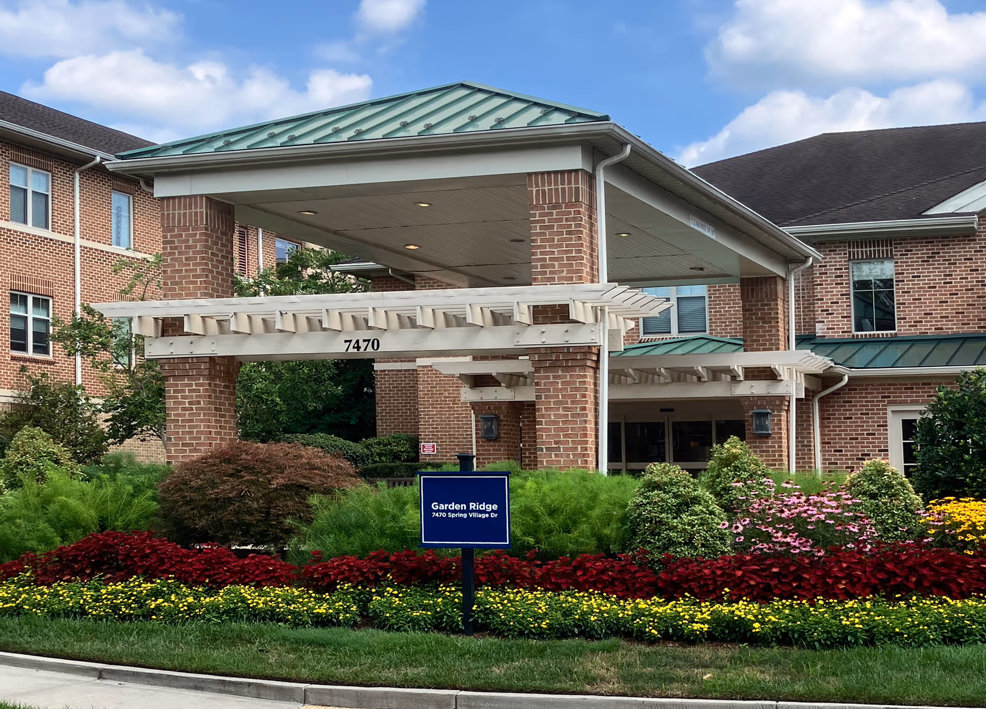 Exterior view of Senior Campus Living building with a green roof, brick columns, and landscaped entrance.