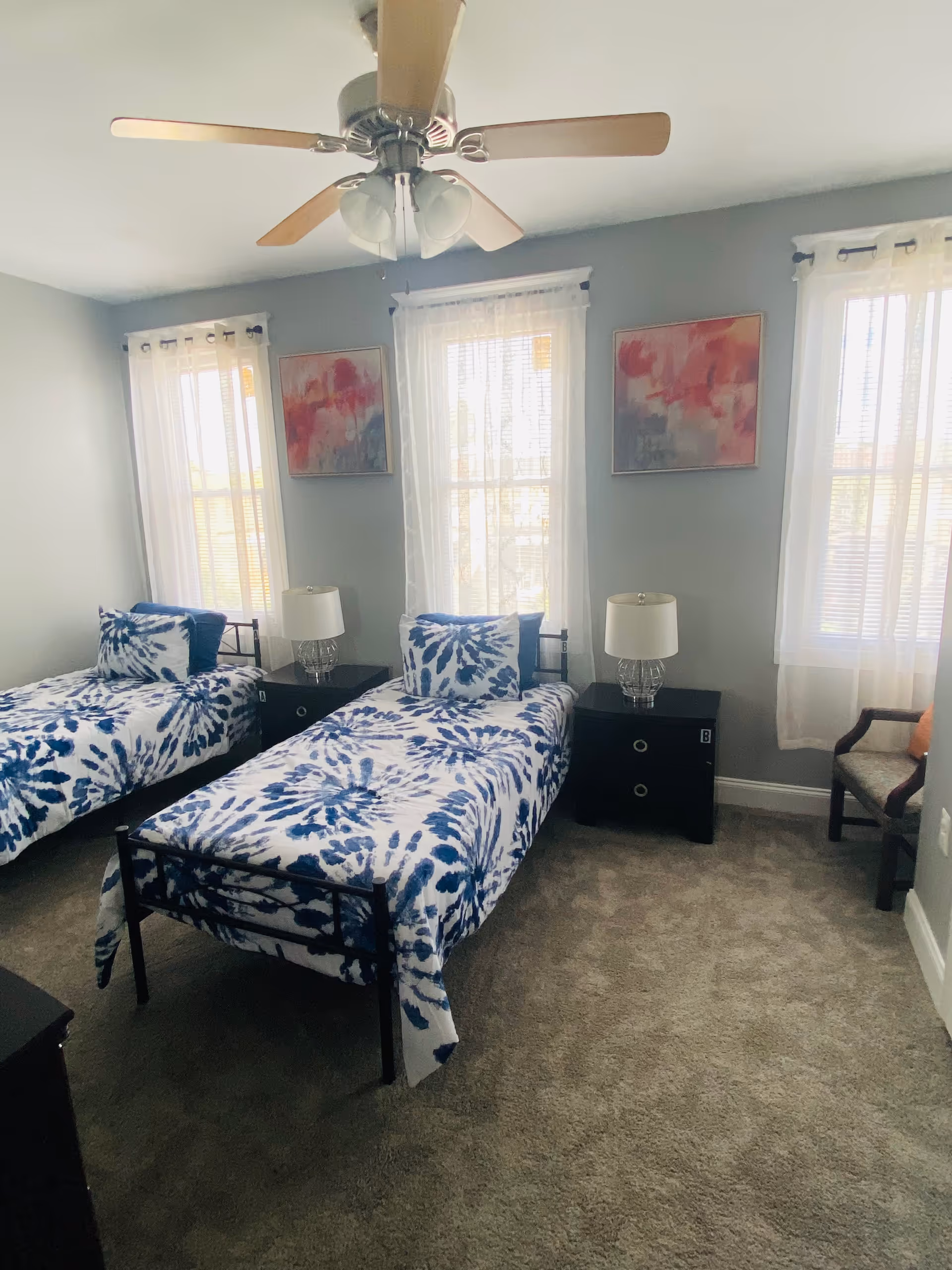 Two twin beds with blue patterned spreads in a bright bedroom.
