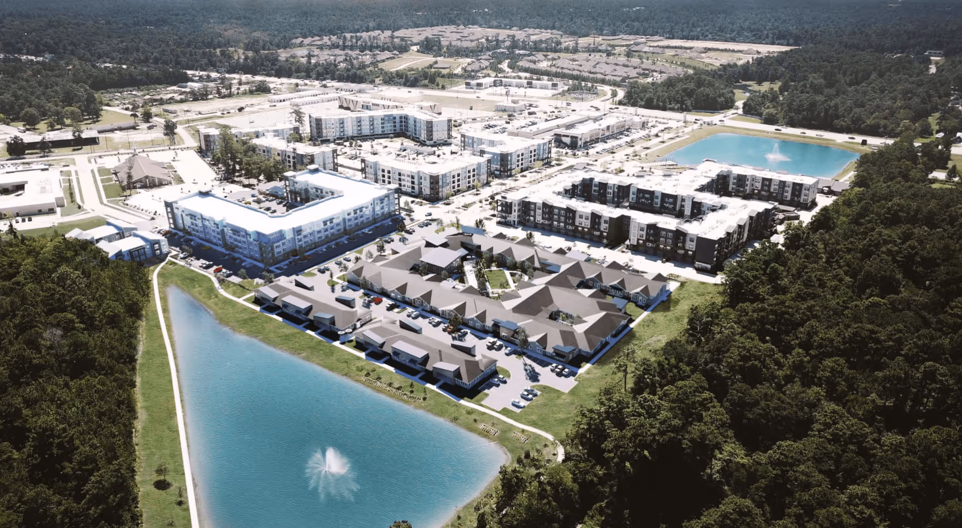 Aerial view of a senior living facility named Landing at Woodland Lakes, showing multiple buildings arranged around landscaped areas, parking lots, and two large water features with fountains, surrounded by wooded areas.