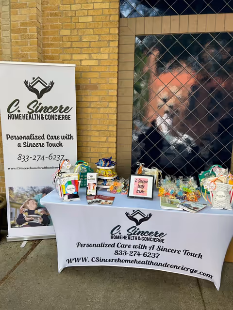 Outdoor display outside brick building with banners and table promoting C Sincere Home Health & Concierge.